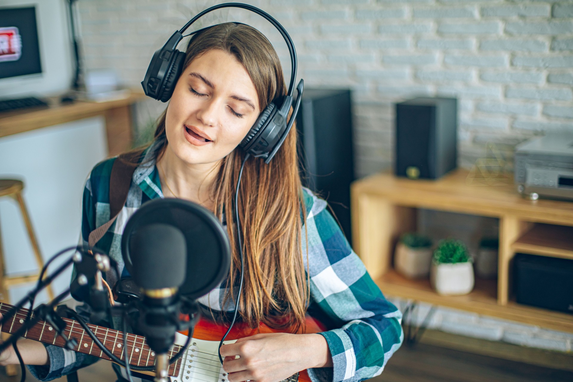 Girl at home playing guitar with microphone and headphones influencer recording, podcast blogger